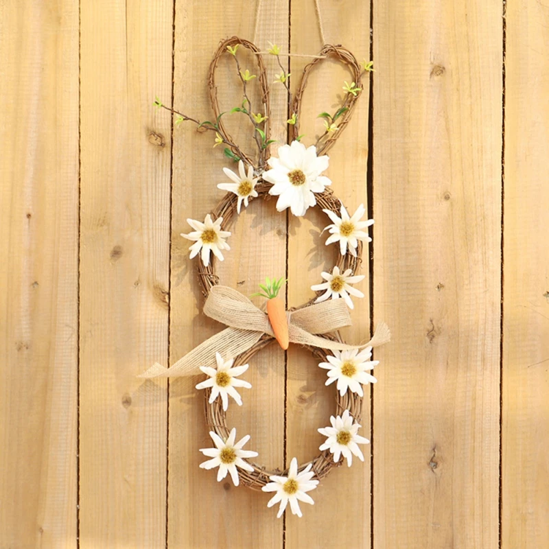 Una corona decorativa elaborada con materiales naturales. Presenta una base circular hecha de ramitas o ramas, adornada con flores blancas que asemejan margaritas. También hay algunos elementos verdes, posiblemente pequeñas ramas u hojas, que contribuyen a la estética natural.