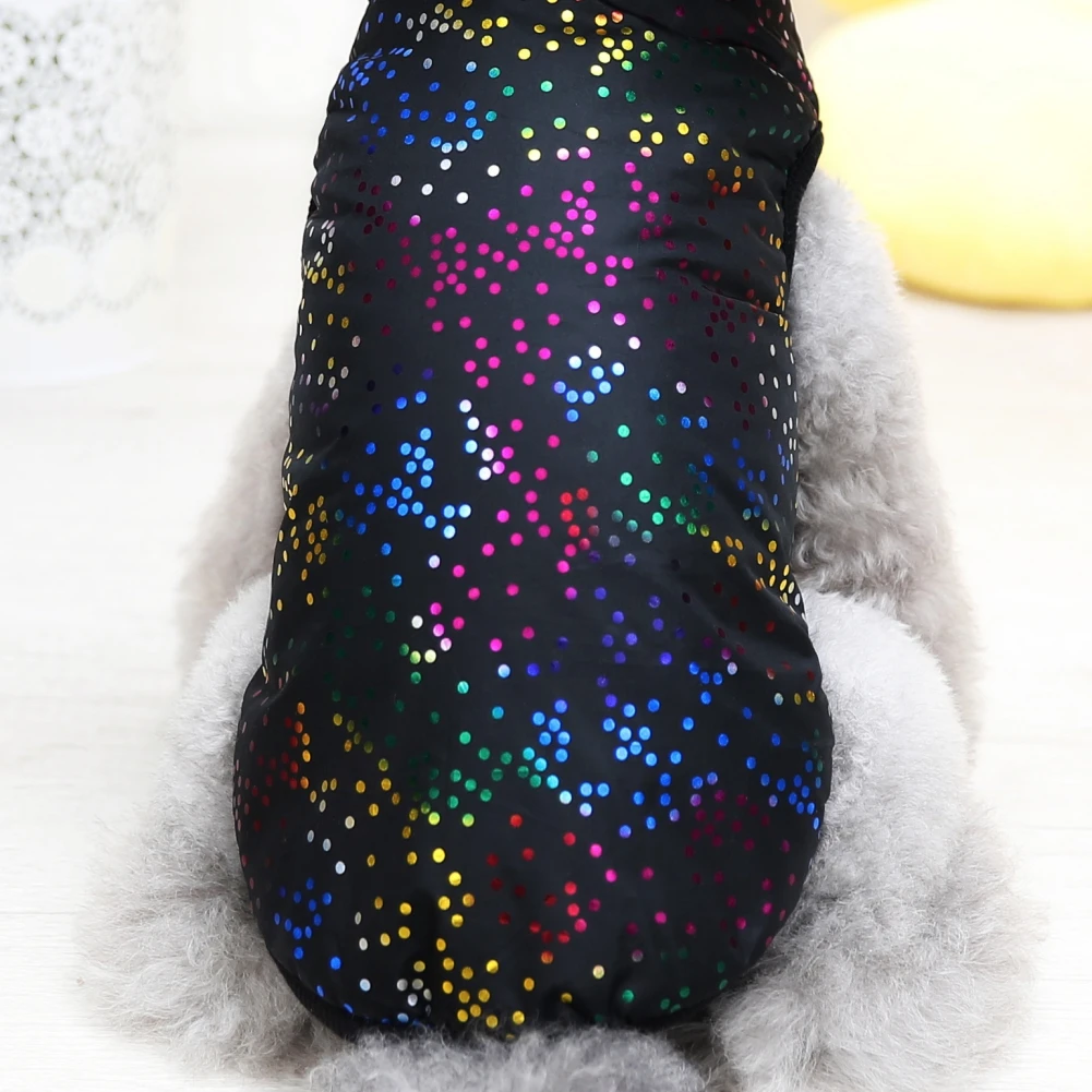 Un perro que viste una prenda negra con un estampado colorido y brillante. La prenda parece ser un tipo de ropa o accesorio diseñado para perros, posiblemente para abrigarse o estar a la moda. El perro tiene un pelaje esponjoso y la prenda le cubre la espalda y parte de las patas traseras.