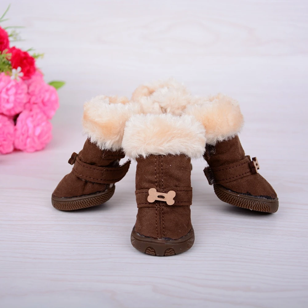 Un par de botas para niños con interior forrado de pelo. Las botas son marrones con un borde de piel blanca alrededor de la parte superior y un pequeño adorno en forma de hueso en el costado. Las botas parecen estar diseñadas para climas fríos, proporcionando calidez con el forro de piel.