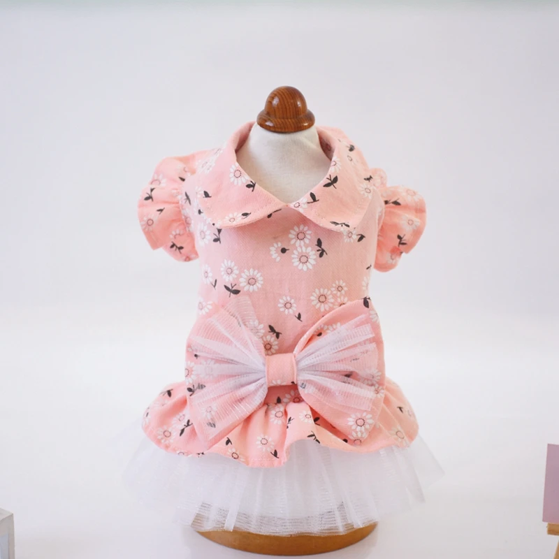 Un maniquí vestido con un vestido rosa con estampado floral. El vestido tiene un lazo en la cintura y parece diseñado para una niña, dada su talla y estilo.