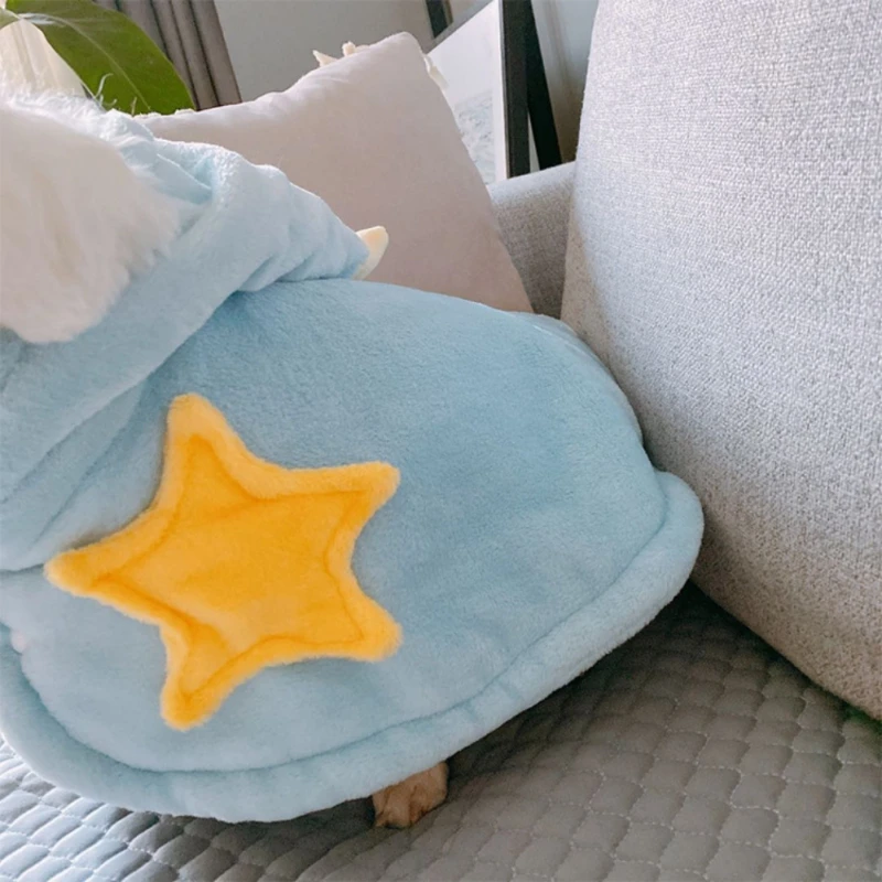 Peluche de cuerpo azul y cabeza blanca, parcialmente cubierto por una manta o un trozo de tela. El juguete tiene una estrella amarilla en la espalda. Parece estar sentado en un sofá o mueble similar, con un cojín o almohada al fondo.