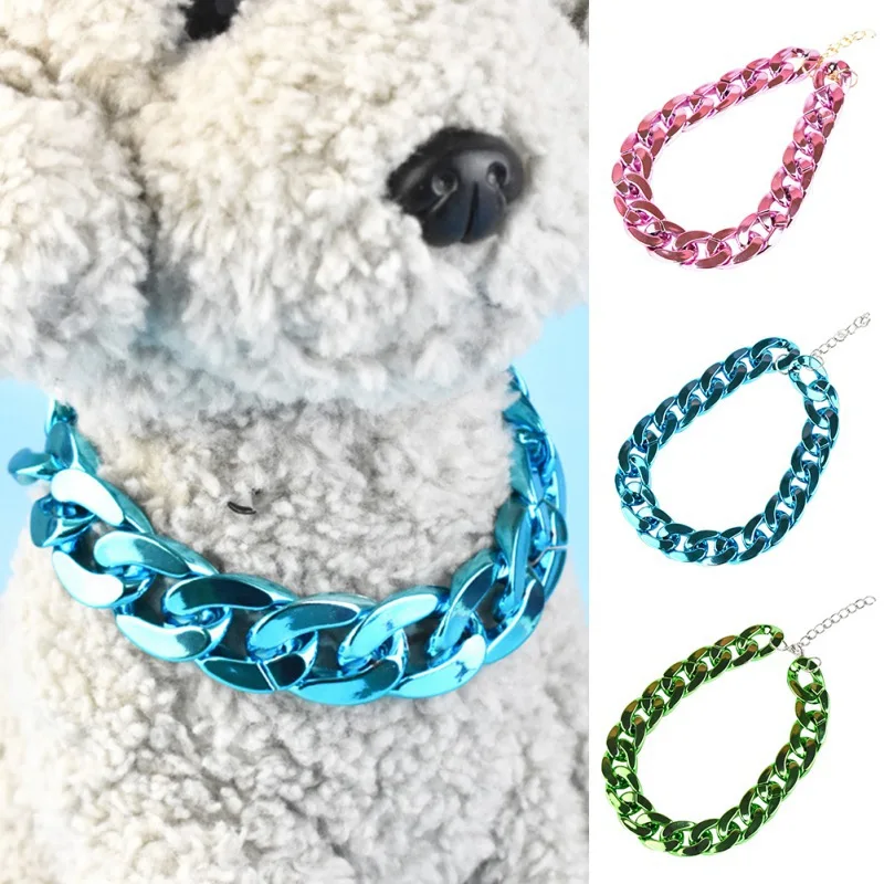 Un osito de peluche blanco con un collar de eslabones de cadena azul. En el lado derecho de la imagen, hay tres pulseras o tobilleras de eslabones de diferentes colores: rosa, azul y verde. Estos accesorios parecen estar hechos de un material brillante, posiblemente metálico.