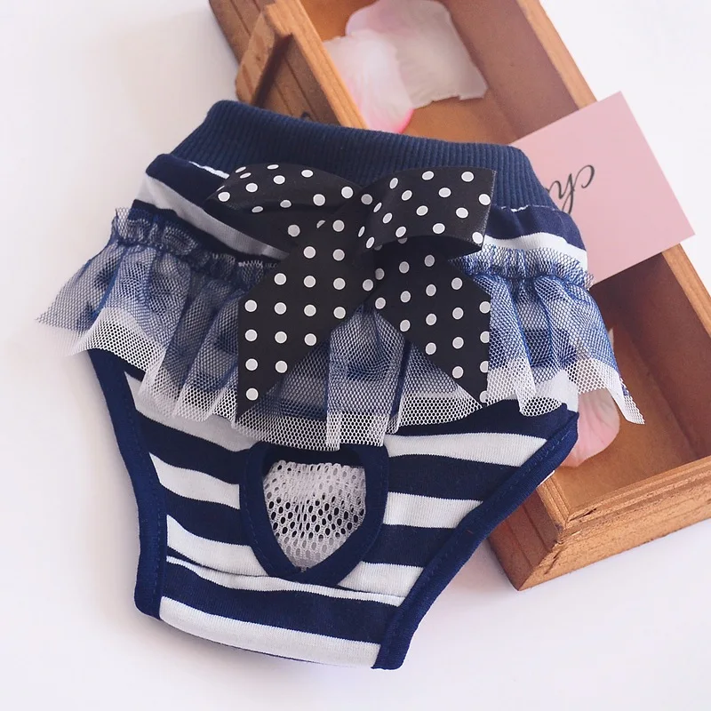 Una ropa interior infantil con un diseño divertido. La ropa interior presenta un patrón de rayas azul marino y blanco con un corte en forma de corazón en la parte delantera. Hay un lazo negro con lunares blancos en la cintura, añadiendo un toque decorativo.