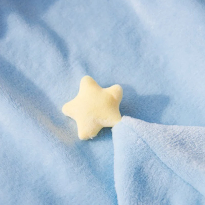 Un pequeño objeto amarillo con forma de estrella colocado sobre una superficie de tela azul. La estrella parece estar hecha de un material blando, posiblemente una tela o una sustancia parecida al fieltro. La superficie de la tela tiene una textura ligera, lo que sugiere que podría ser una manta o un trozo de tela.