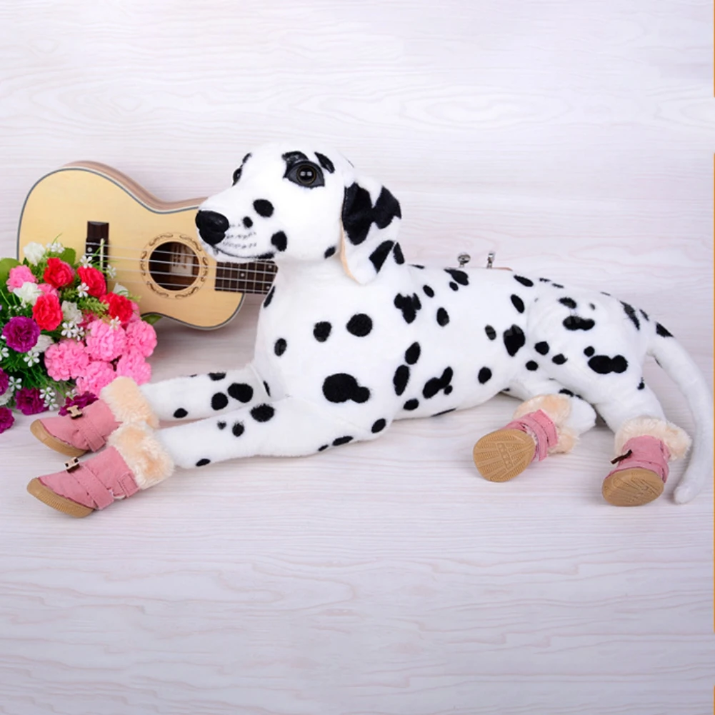 Un peluche de un perro dálmata acostado de lado. El perro lleva botas rosas y tiene una guitarra al lado. También hay algunas flores rosas al fondo. El escenario parece ser una fotografía escenificada, posiblemente para la exhibición de un producto o publicidad.