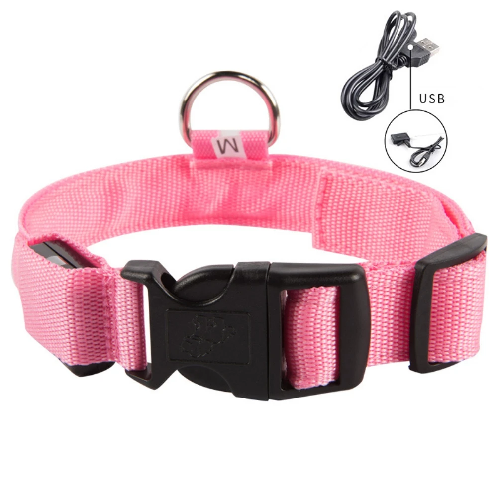 Un collar de perro rosa con una hebilla negra y un anillo plateado para sujetar la correa. También hay un cable USB con un conector negro y un cable blanco, que probablemente sea un cable de carga para un dispositivo.