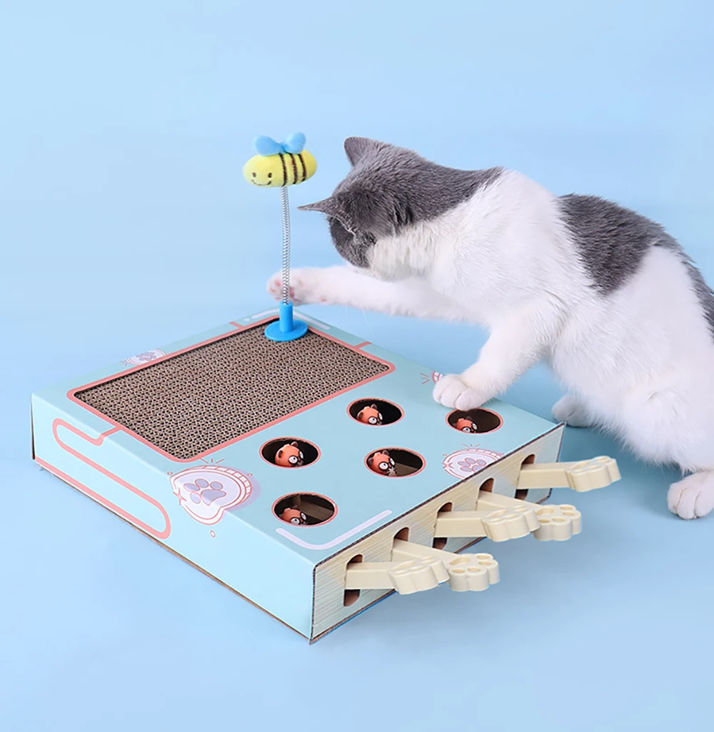 Un gato interactuando con un juguete. El juguete parece ser una caja con una variedad de elementos interactivos, como agujeros para que el gato meta sus patas, una superficie para rascar y una abeja de juguete en un palo contra el cual el gato parece estar golpeando.