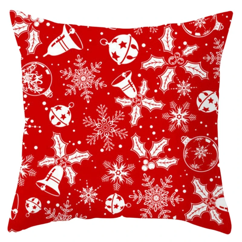 Una almohada roja con un patrón navideño festivo. El patrón incluye varias decoraciones navideñas, como campanas, hojas de acebo, copos de nieve y adornos. Los colores son predominantemente el rojo y el blanco, que son colores tradicionales asociados con la Navidad.