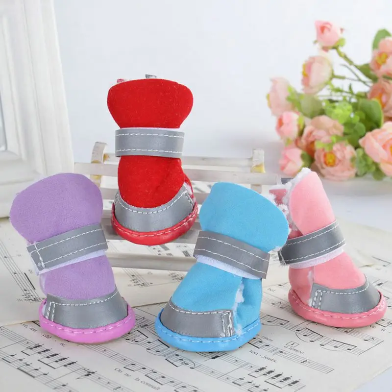 Una colección de pantuflas de felpa coloridas. Hay cuatro pares en total, cada uno con un color diferente: rojo, morado, azul y rosa. Cada par tiene una correa gris alrededor de la parte superior, que probablemente sirve como mecanismo de cierre.