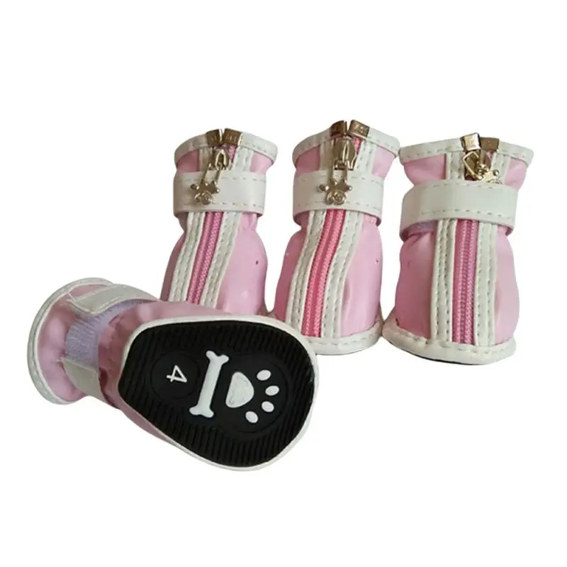 Un par de botines para perros de color rosa. Estos botines están diseñados para proteger las patas de un perro de diversos elementos como suciedad, barro, superficies calientes o temperaturas frías. Tienen una correa que pasa por encima de la pierna del perro para asegurarlos en su lugar.