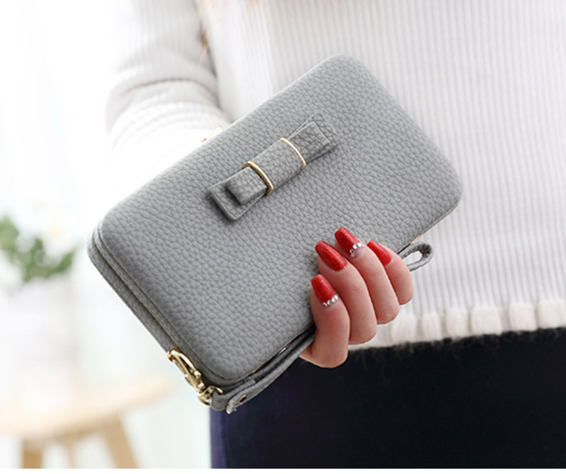 hall nahast rahakott lipsukujulise detailiga, mida hoiab käes naine