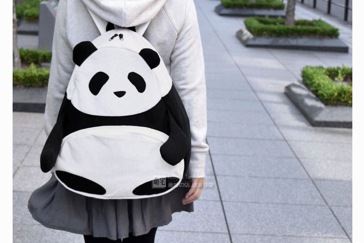 must-valge panda kujuline seljakott halli kapuutsiga jopega inimese seljas