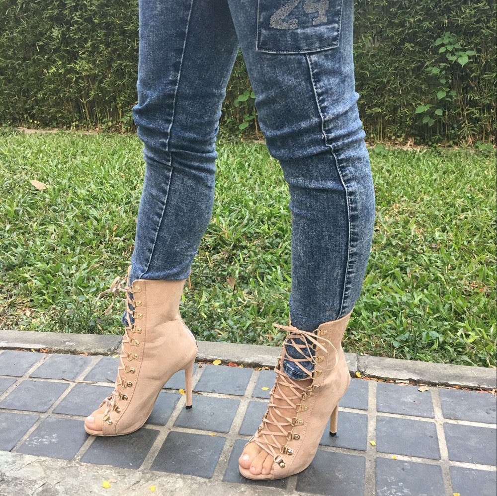 beežid kõrge kontsaga paeltega saapad naise jalas, taustal muru