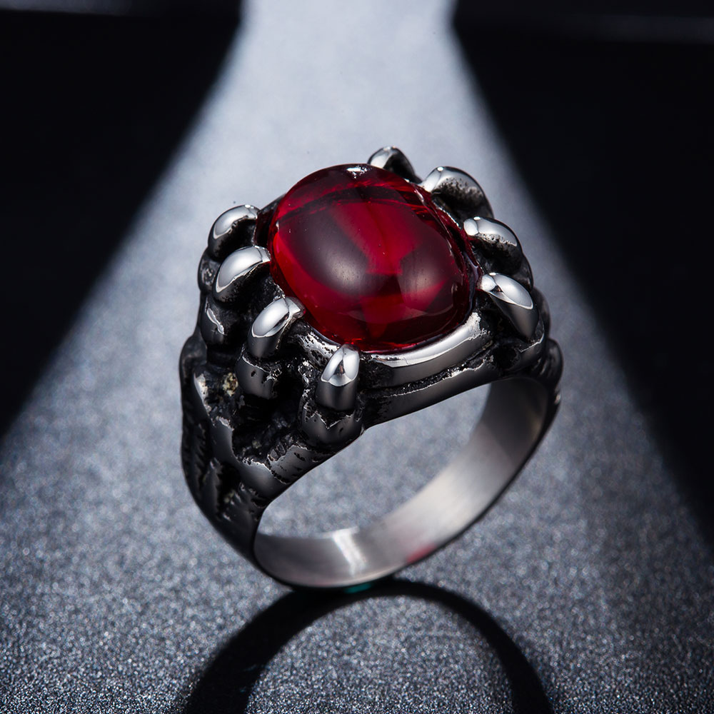 hõbedane sõrmus punase kiviga, mida hoiavad lohe küünised