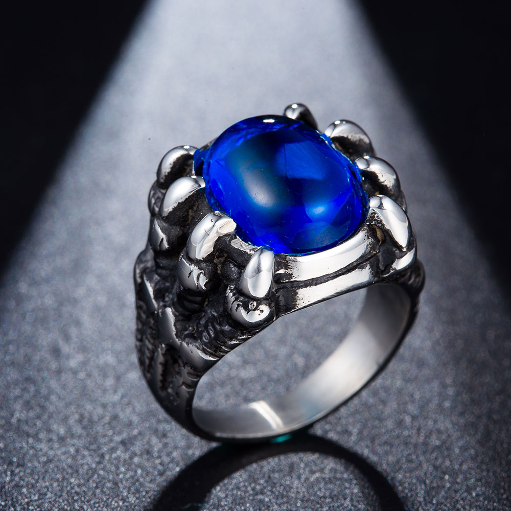 hõbedane sõrmus sinise kiviga, mida hoiavad lohe küünised