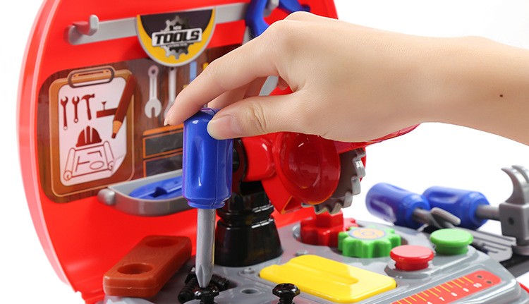 laste mängu tööristakomplekt koos värviliste tööriistadega ja käsi, mis hoiab kruvikeerajat