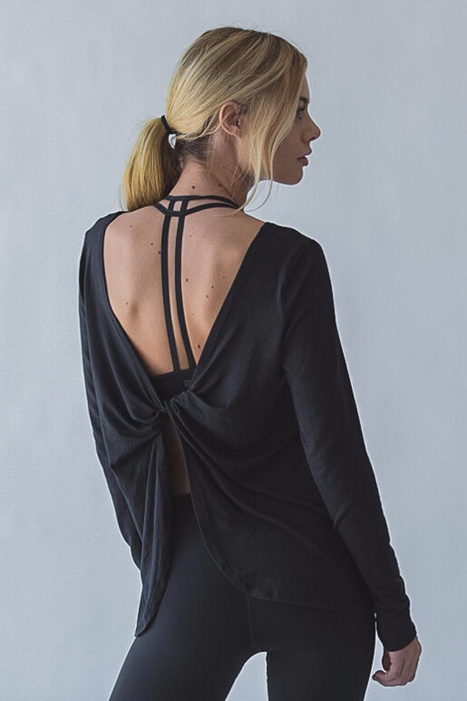 naine kannab musta pikkade varrukatega särki, millel on avatud seljaosa ja rihmad