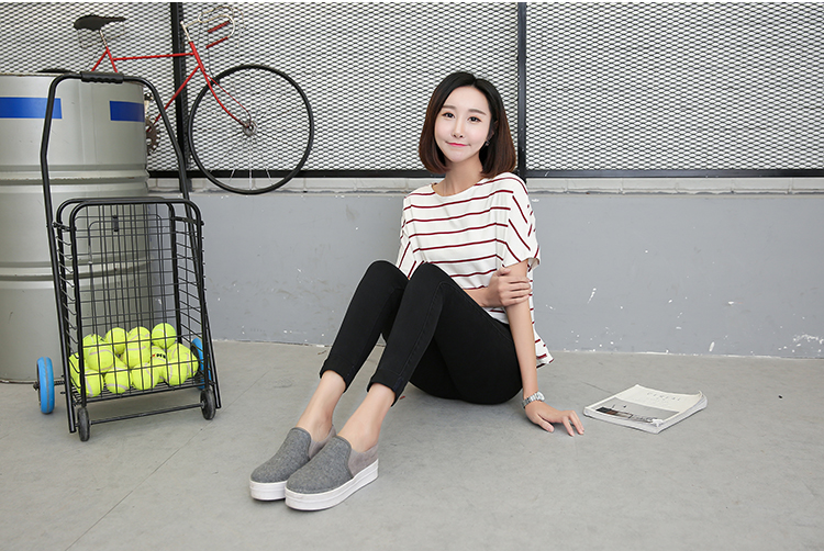 naine istub põrandal mustades ja tumehallides teksades