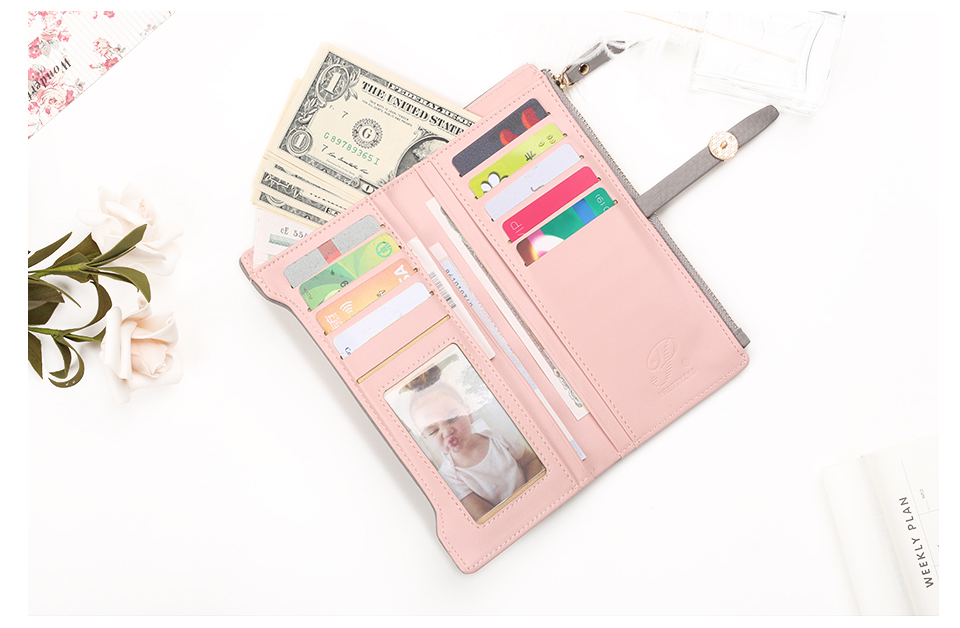 roosa naiste rahakott lahtiselt, sees kaardid ja dollarid