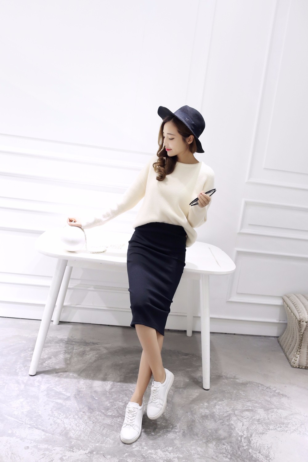 naine kannab tumesinist pliiatsseelikut ja valget kampsunit