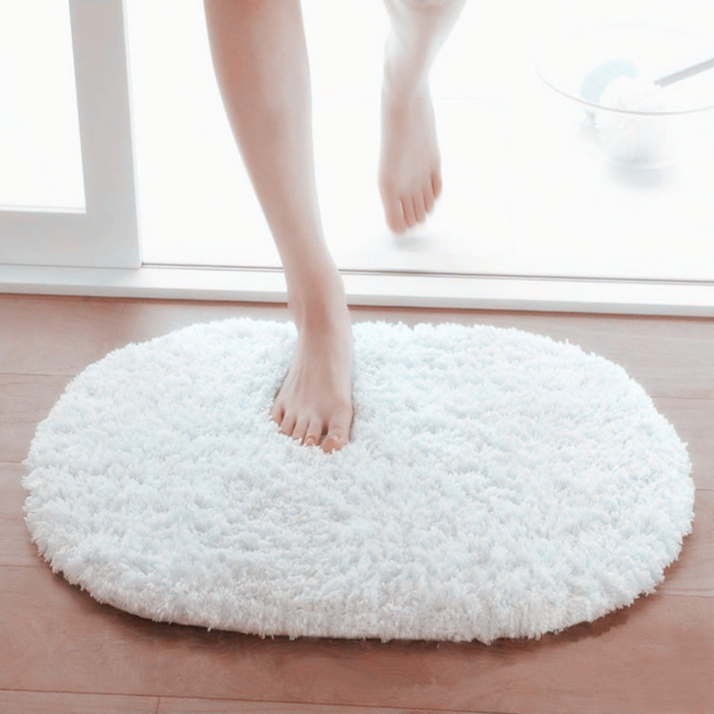 valge ümmargune pehme vannitoamatt puidust põrandal