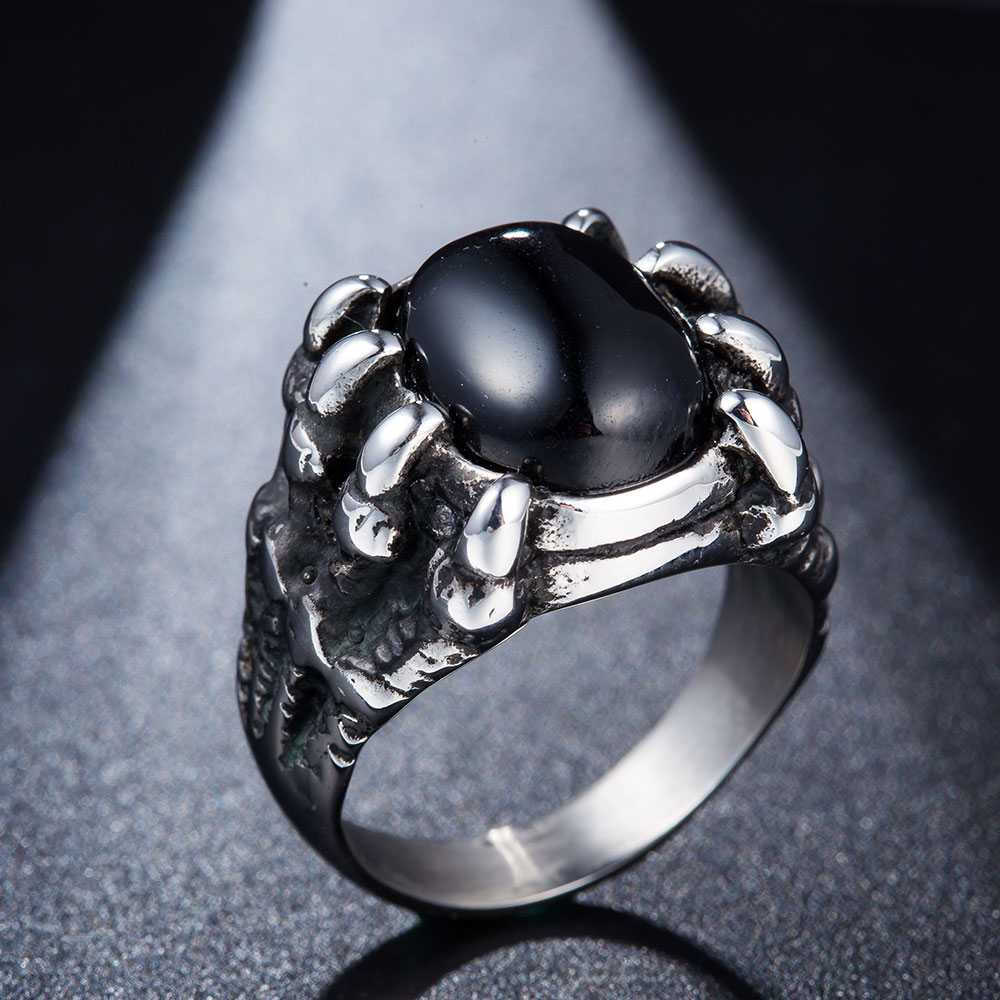 hõbedane sõrmus musta kiviga, mida hoiavad lohe küünised