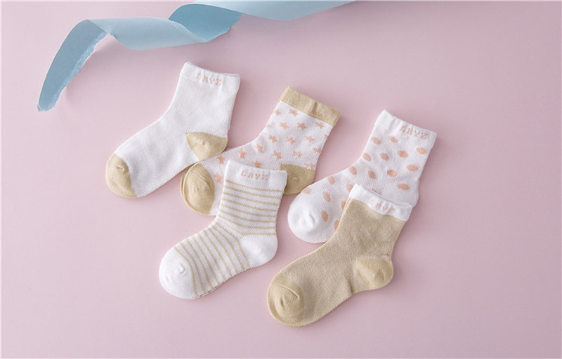 viis paari erineva mustriga puuvillaseid laste sokke roosa taustal