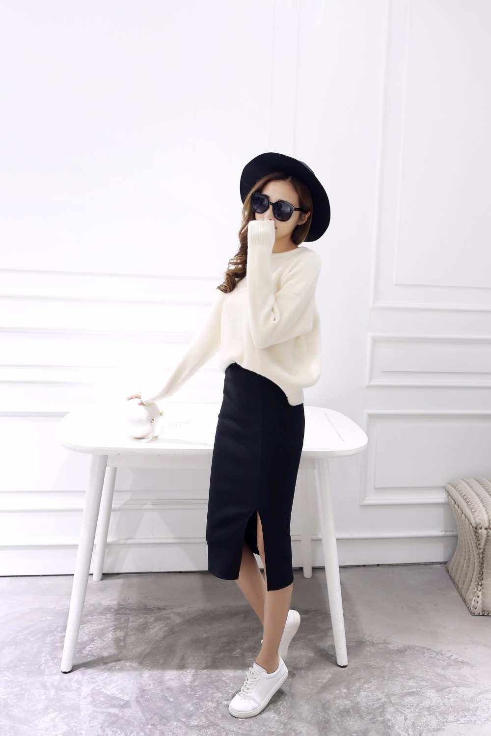 naine kannab musta pliiatsseelikut ja valget kampsunit