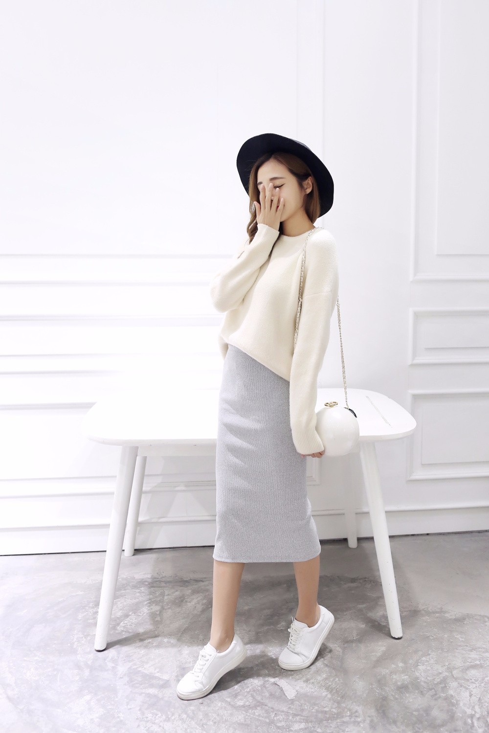 naine kannab halli pliiatsseelikut ja valget kampsunit