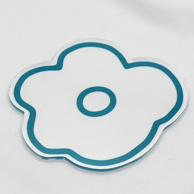 Una pegatina o calcomanía con un diseño floral estilizado. La flor tiene un contorno sencillo con un borde azul y un centro blanco, dándole un aspecto minimalista y moderno. La pegatina se coloca sobre una superficie blanca, que contrasta con el borde azul, haciendo que el diseño destaque.