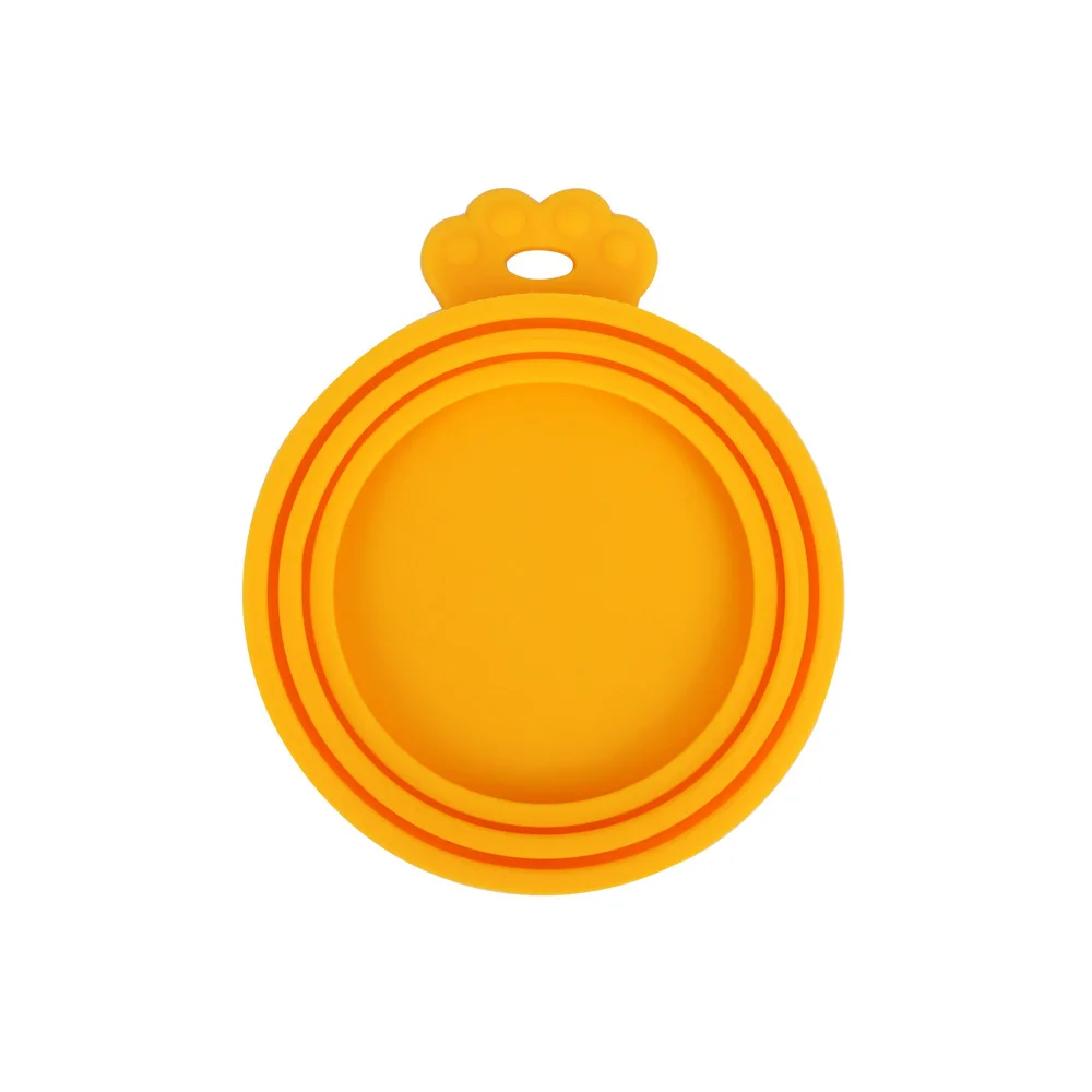 Un objeto amarillo que parece ser una insignia o emblema circular con un borde elevado. En la parte superior de la insignia hay un pequeño elemento decorativo que parece una flor estilizada o un rayo de sol. El fondo es blanco liso, lo que hace que el color amarillo de la insignia destaque de forma destacada.