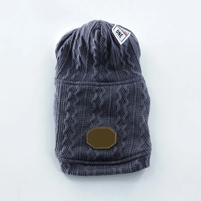 Un gorro de punto. Parece ser de un color gris oscuro con un patrón acanalado y un pequeño parche redondo de color marrón en el frente.