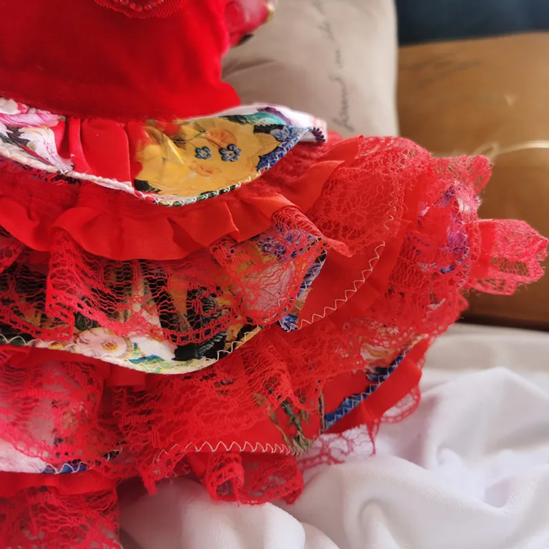 Un primer plano de una prenda de vestir, que parece ser una falda o un vestido con dobladillo con volantes. La tela tiene un patrón floral y está cubierta con encaje rojo o un material similar.