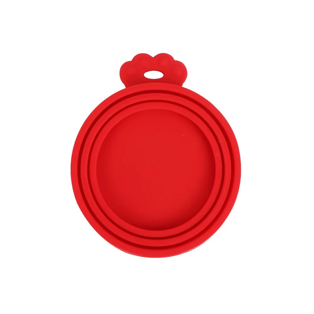 Un objeto circular rojo con un agujero en el centro. Parece ser un elemento simple, plano y circular, posiblemente una tapa o cubierta de algún tipo. En la parte superior del objeto hay un pequeño elemento decorativo que parece una flor o un corazón, también de color rojo.