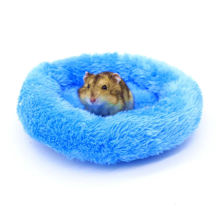 Un pequeño hámster sentado dentro de un objeto circular azul, esponjoso, que parece ser un juguete o una pieza de ropa de cama diseñada para mascotas pequeñas. El hámster parece cómodo y está frente a la cámara.