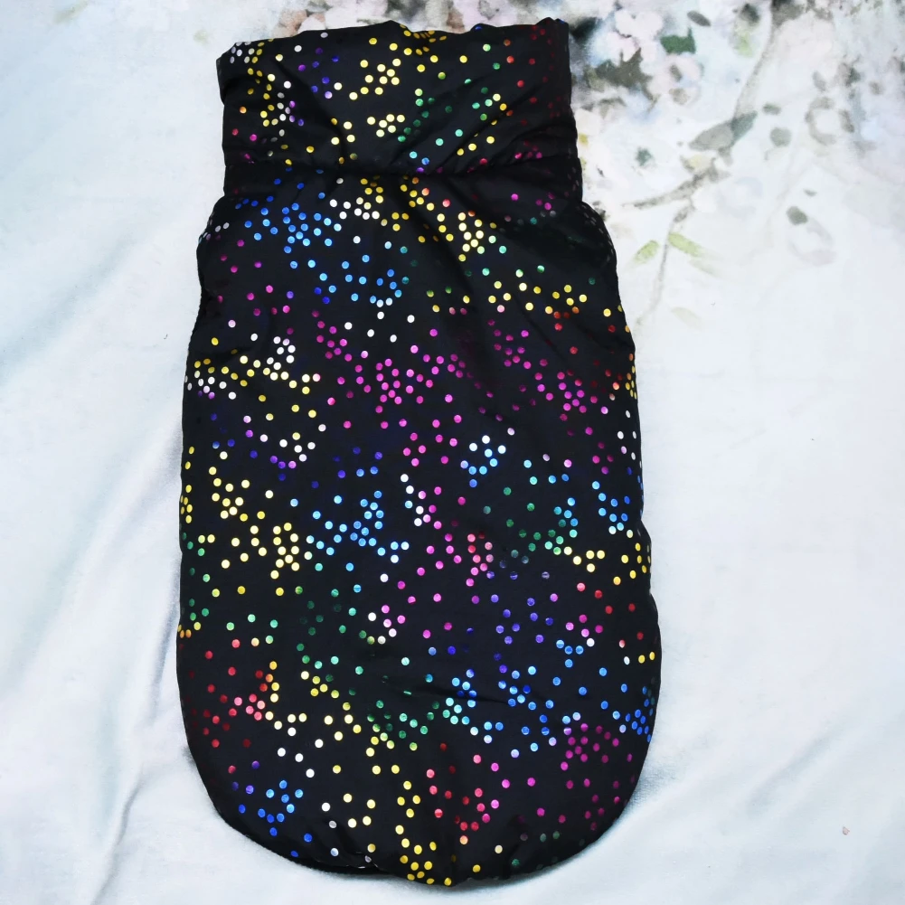 Una prenda de tela negra con un patrón de puntos de colores. Parece ser una bolsita o un bolso pequeño, posiblemente diseñado para llevar objetos pequeños o como accesorio decorativo.