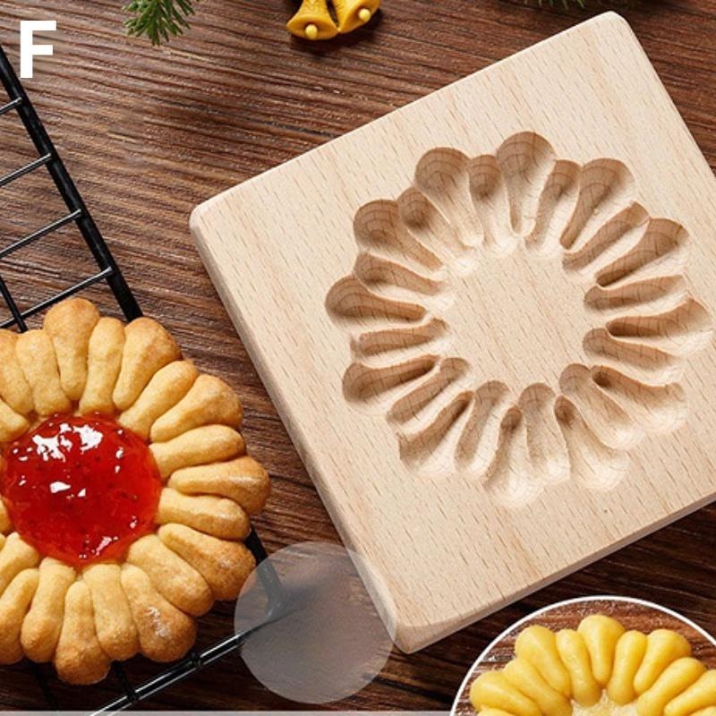 A Wooden 3D Cookie Cutter, designed for Christmas biscuits with elegant carved flower patterns, is displayed next to a baked cookie showcasing the same intricate design and featuring a red jam center. A cooling rack and pine branches add to the cozy atmosphere.