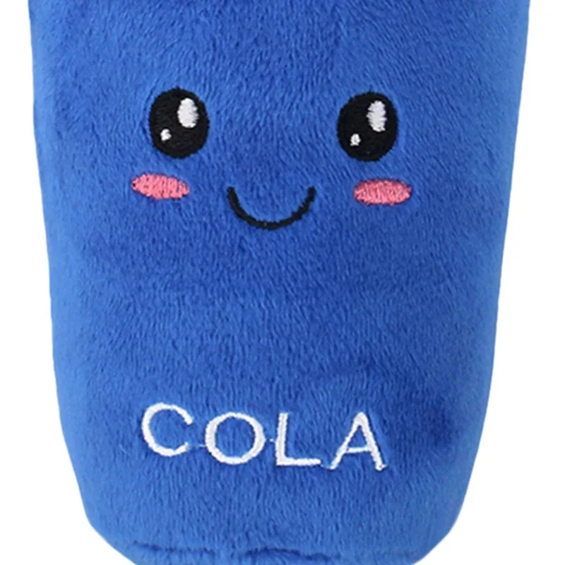 Un peluche con cuerpo azul y cara sonriente. Tiene dos ojos negros con pupilas blancas y una pequeña boca rosada. El juguete también tiene la palabra COLA bordada en su cuerpo.