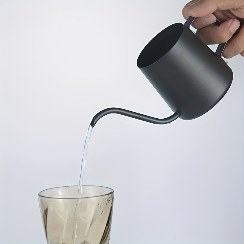 A hand pours water from a sleek, black gooseneck kettle into a transparent glass, presenting it as a sophisticated coffee accessory. The plain white background highlights the graceful flow of water and an elegant design reminiscent of the 304 Stainless Steel Milk Cup Coffee House Essential High-Quality Coffee Set.