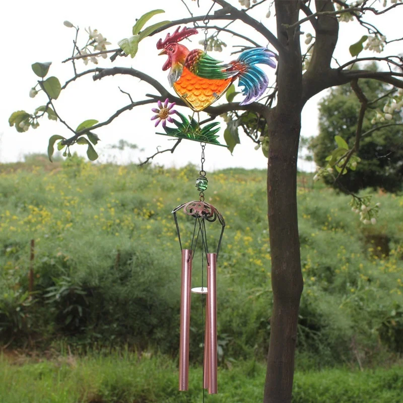 La campana de viento colorido con un diseño de gallo vibrante agrega encanto a un entorno de jardín sereno