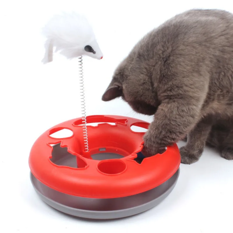 Un gato interactuando con un juguete. El juguete parece ser un objeto circular rojo con un agujero en el centro, posiblemente diseñado para que el gato juegue o sostenga golosinas.