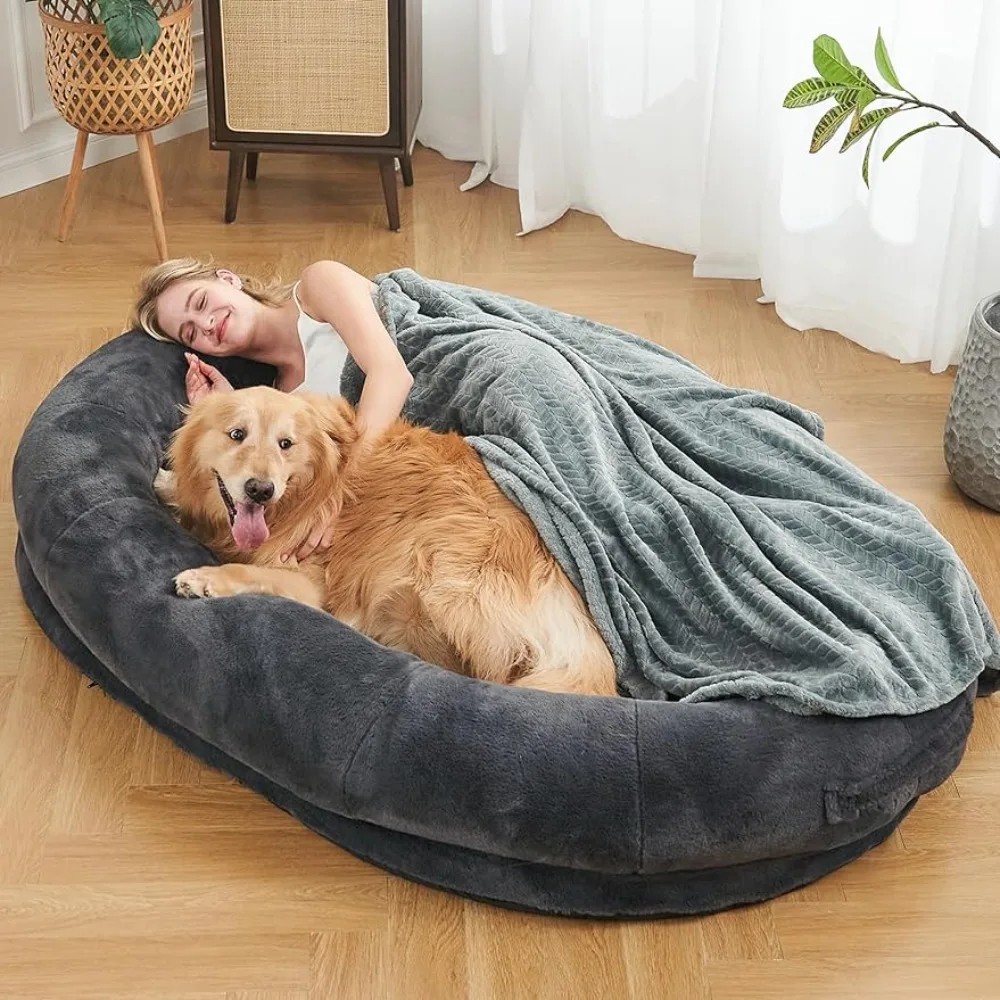 A woman lying in a cozy dog bed with a dog.