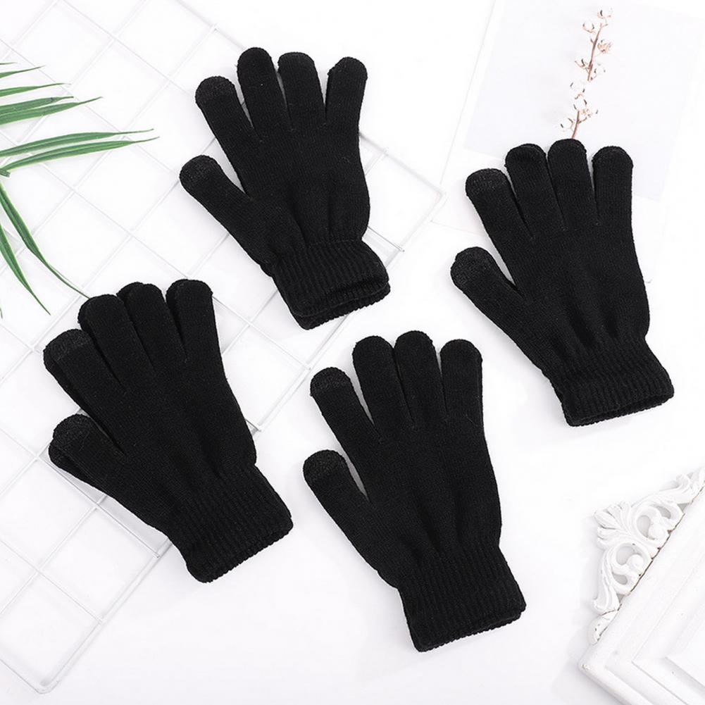 Mustad laste soodsad sõrmikud valgel laual koos dekoratiivsete elementidega, valmistatud pehmest ja soojast materjalist.