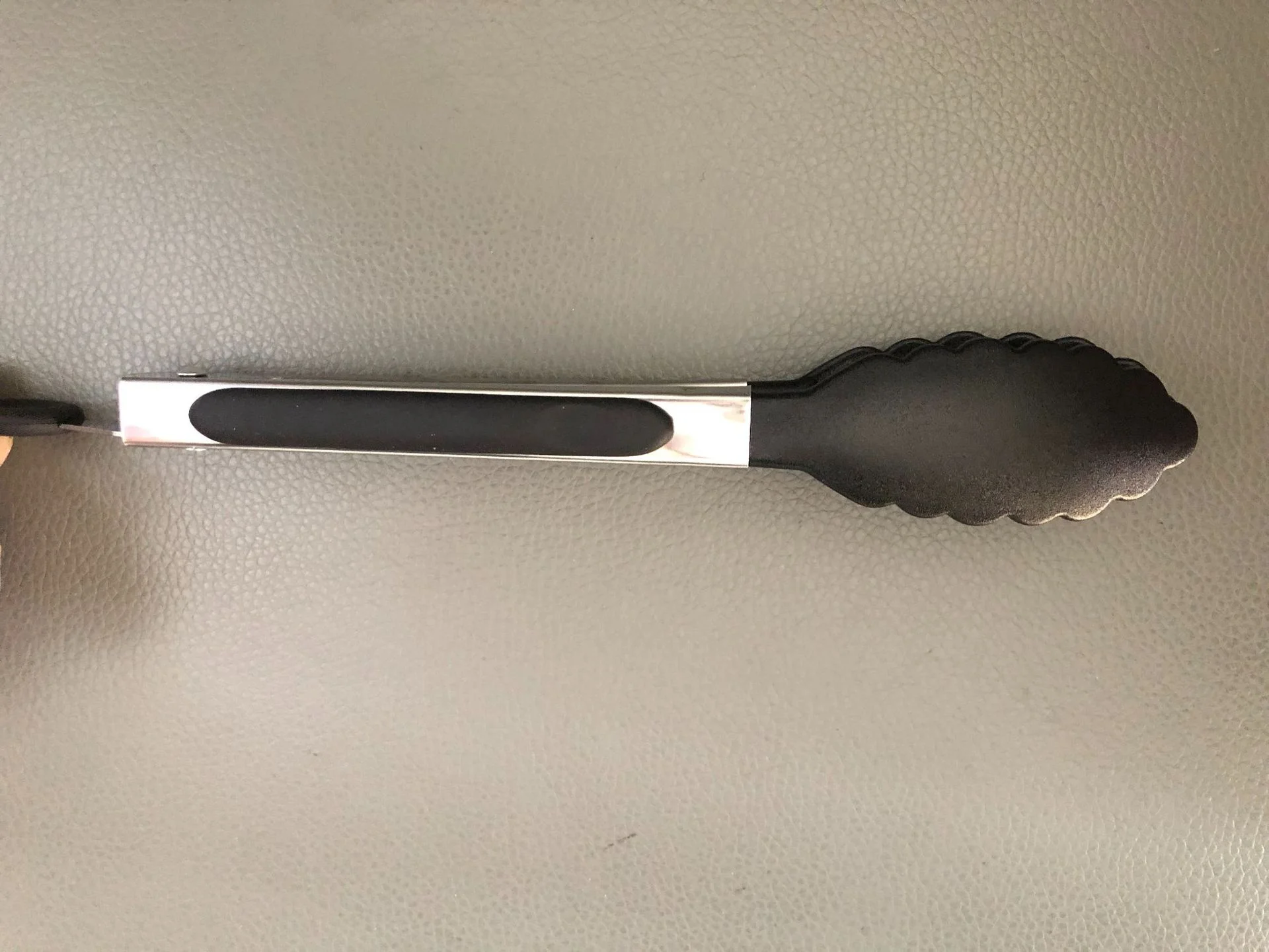 Una cuchara negra y plateada está sobre una mesa.