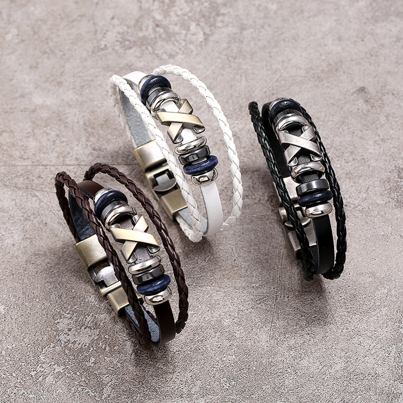 Three leather bracelets with metal accents on a gray surface