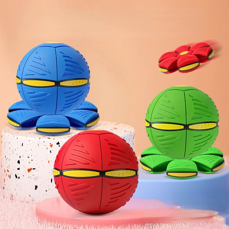Three spherical toy balls in blue, red, and green are displayed on stands. One ball, designed as The Stuff Box's Flying Saucer for Outdoor Training and Play, is shown in midair, partially transformed into a disc shape.