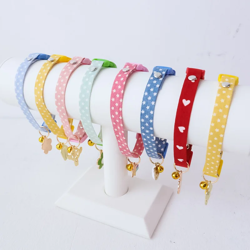 Una colección de pulseras o brazaletes coloridos exhibidos sobre un soporte blanco. Cada pulsera tiene un diseño y color diferente, y están adornadas con diversos charms, como cascabeles y otros elementos decorativos. Las pulseras parecen estar diseñadas para niños o como complementos para un evento o actividad específica.