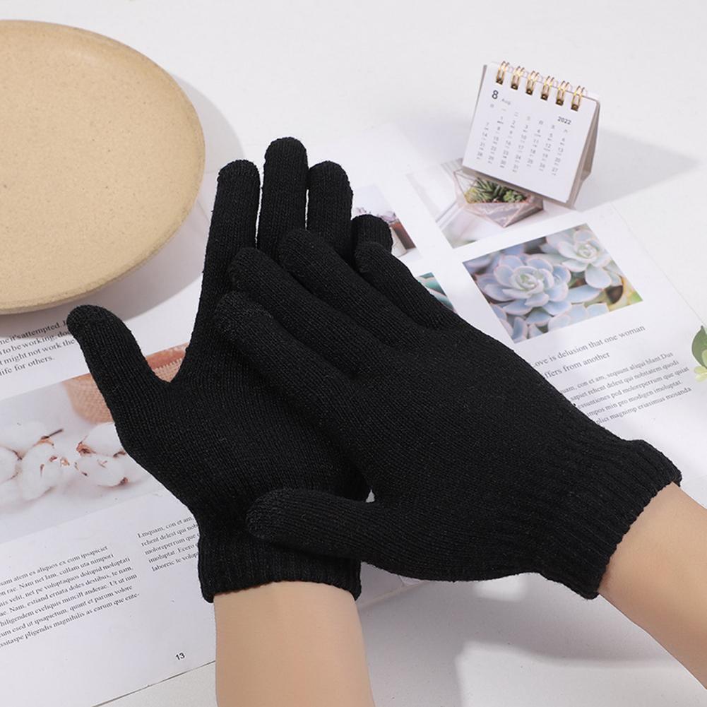 Kahe paari kätega mustad Soodsad sõrmikud lastele asetsevad heledal laual ajalehtede ja kalenderaamatu kõrval. Need kindad on valmistatud pehmest materjalist, pakkudes soojust ja mugavust jahedatel päevadel.